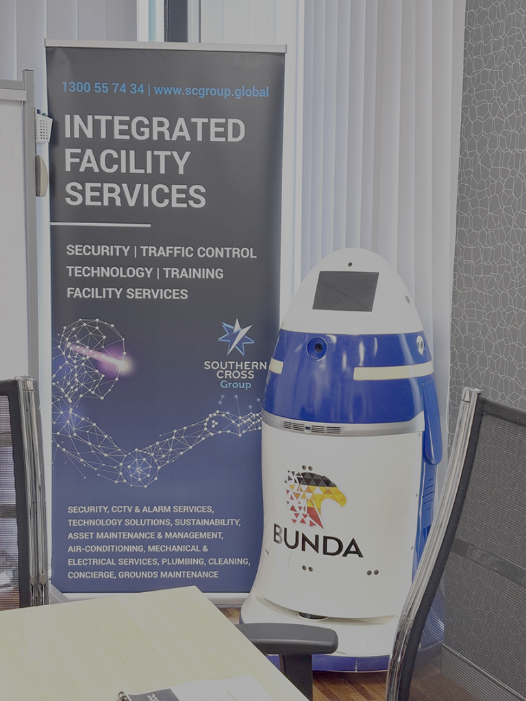 Autonomous security robot branded BUNDA positioned beside Southern Cross Group integrated facility services banner.